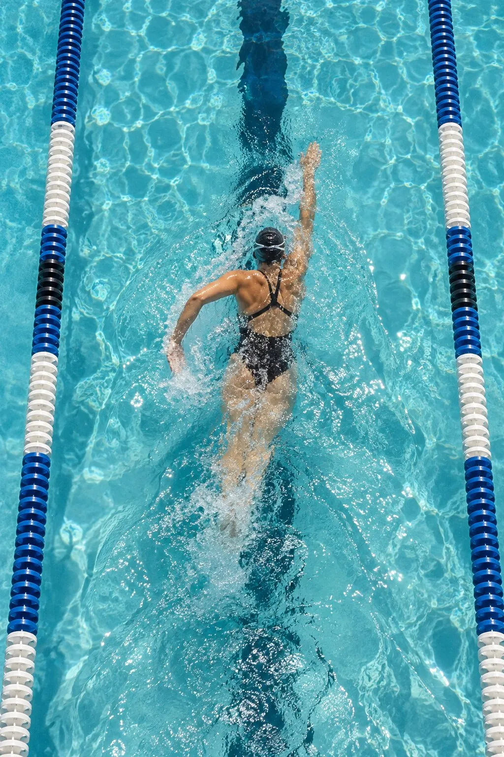 A swimmer doing laps in an outdoor pool, seen from above
